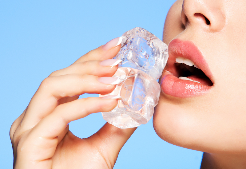 Close up of a woman applying ice to her face