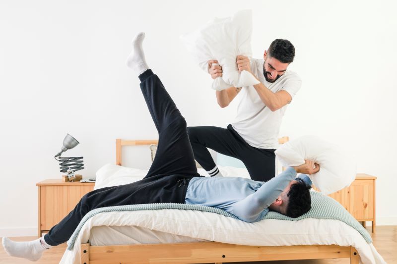 Couple ayant une bataille d'oreillers à la maison 
