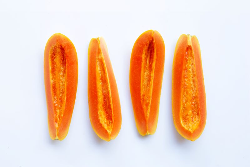 Four half papayas on white background