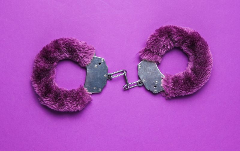 Purple fluffy handcuffs on purple background