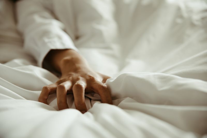 Hand gripping white bed sheet