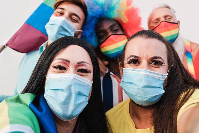 Happy friends with masks and rainbow flags