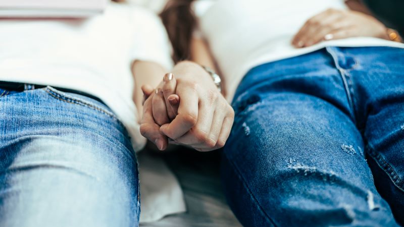 Intimate couple lying down holding hands