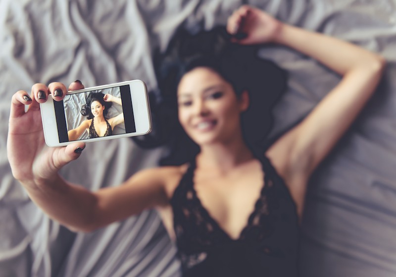 Femme prenant un selfie sur le lit