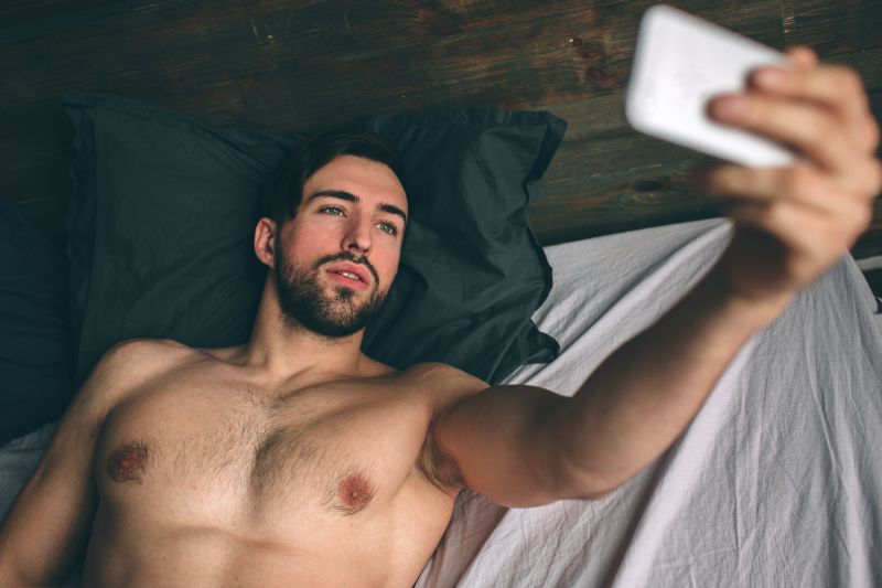 Homme barbu prenant selfie au lit