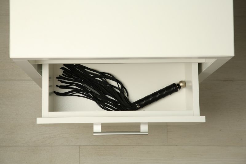 Black BDSM whip in bedside drawer