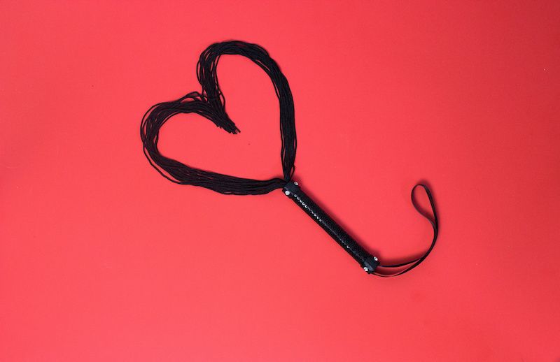 Black BDSM whip in love heart shape