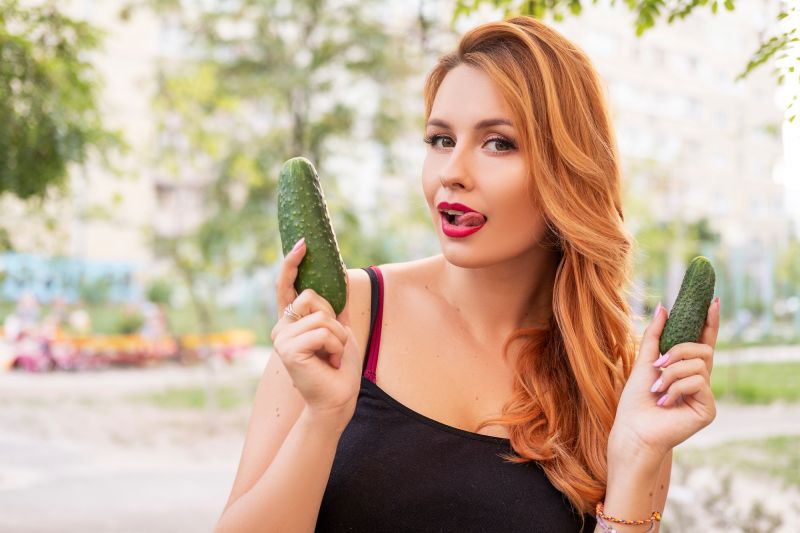 Cheeky woman holding two cucumbers