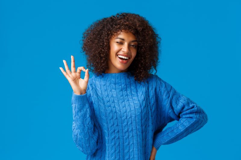 Cheerful young woman making Okay sign