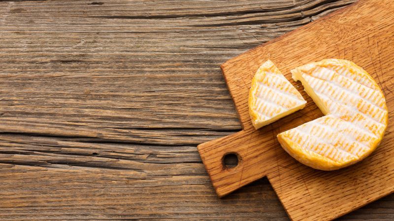 Planche à découper avec fromage sur table