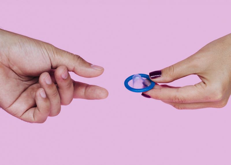 Close up hands passing blue condom