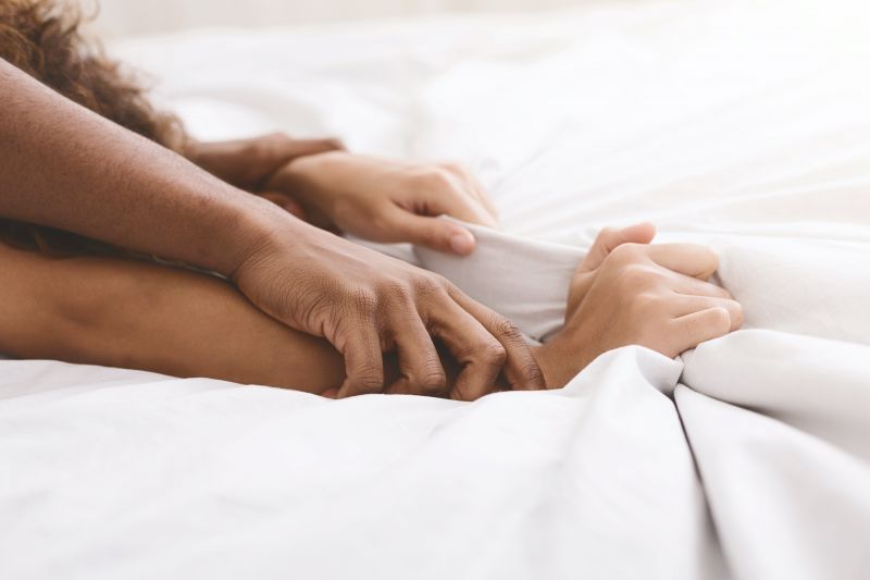 Close up of hands gripping bedsheets