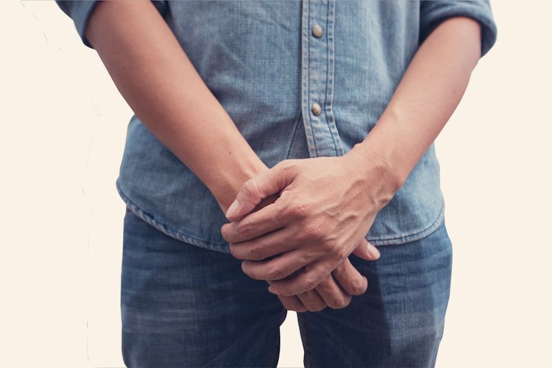 Gros plan d'un homme couvrant son entrejambe avec ses mains