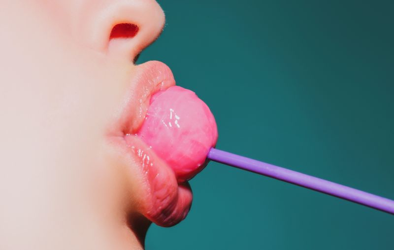 Close up woman sucking pink lollipop