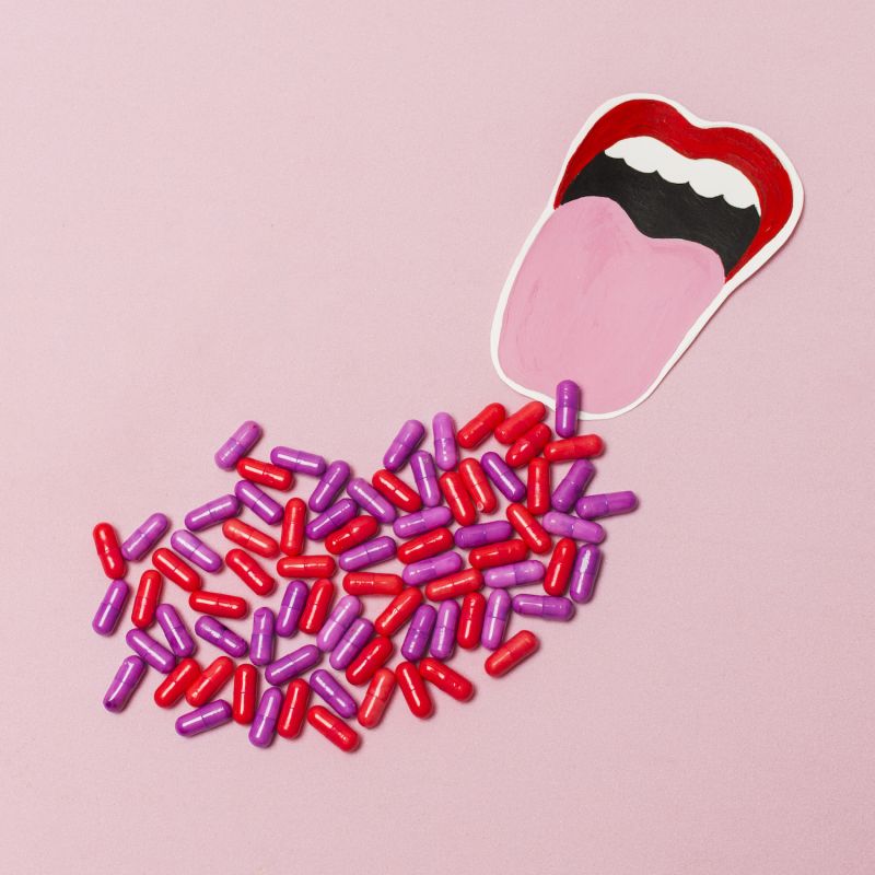 Pills on pink background with drawn red mouth