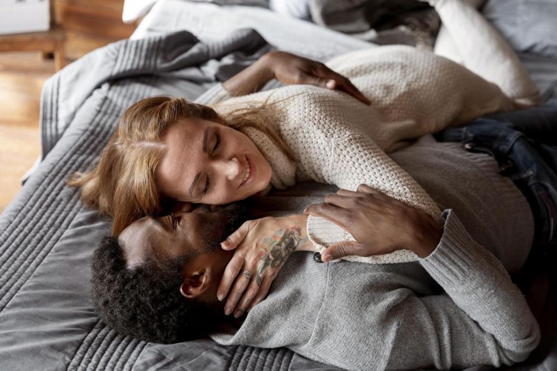 Couple cuddling and laughing in bed