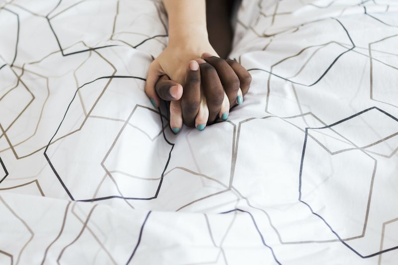 Couple holding hands in bed