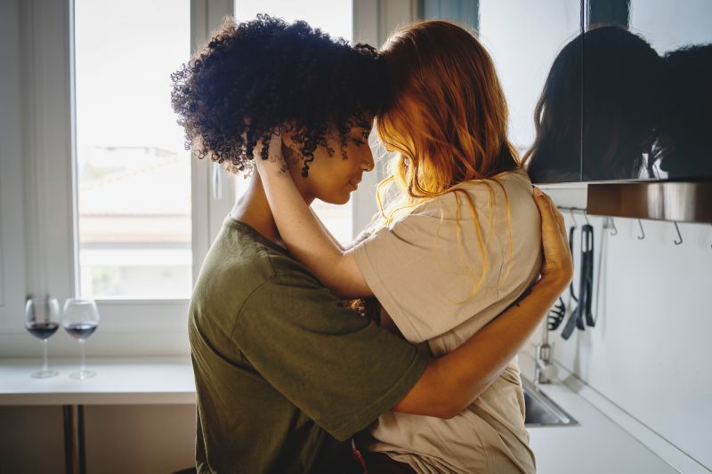 Couple hugging faces touching in kitchen