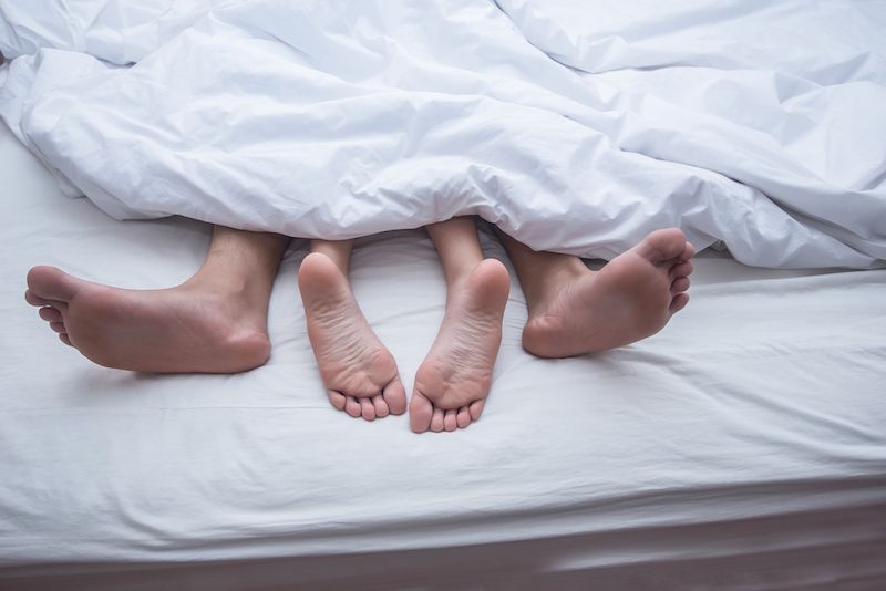 Men and woman feets under the sheets