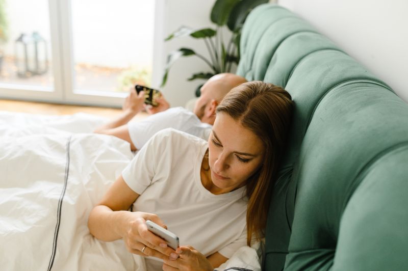 Couple au lit face à l'aide de téléphones intelligents
