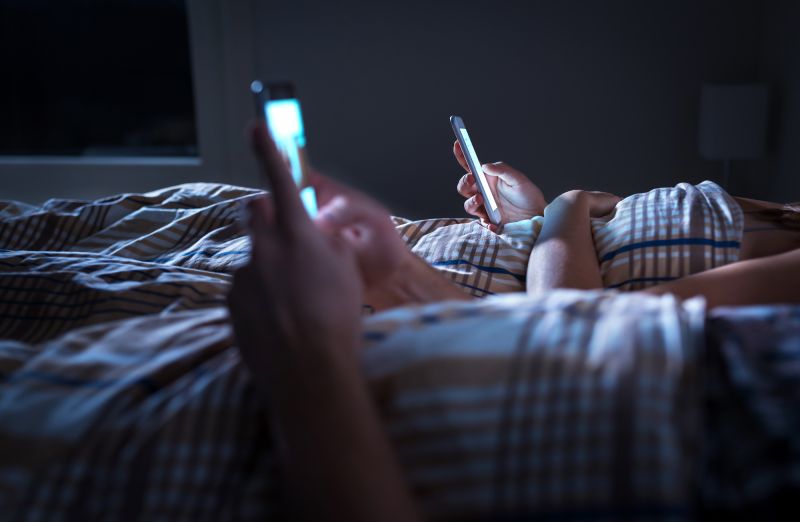 Couple in bed at night on smartphones