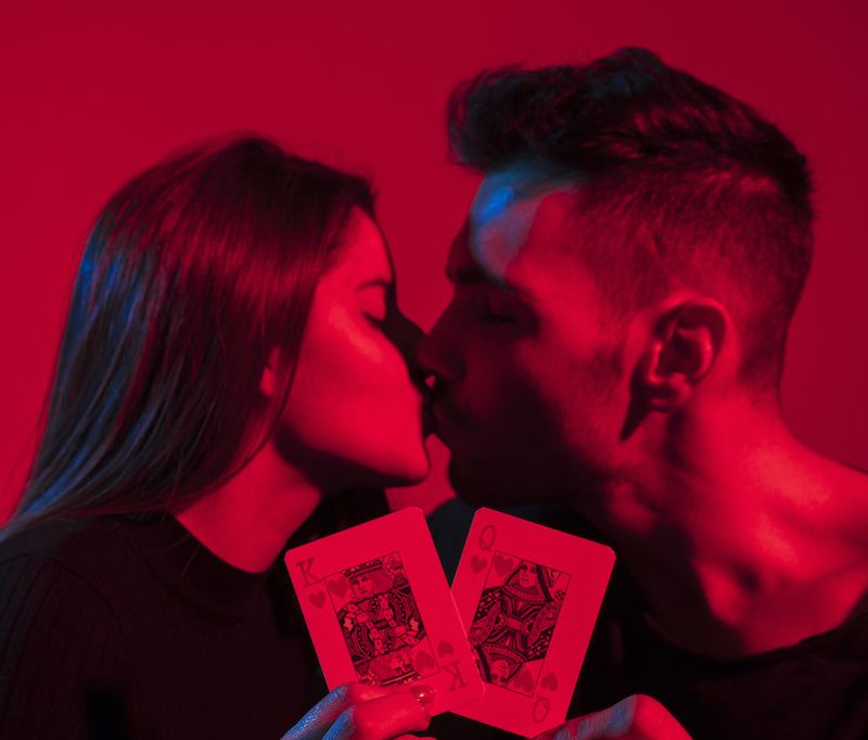 Couple s'embrassant et tenant des cartes à jouer