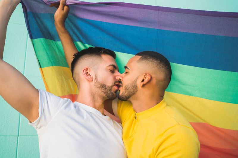 Couple s'embrasser devant le drapeau de la fierté