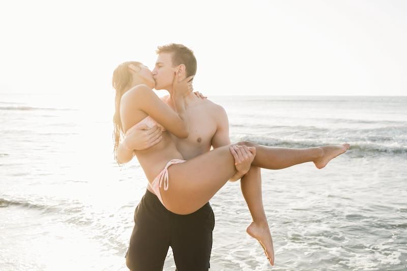 Couple s'embrassant sur la plage avec un homme prenant sa petite amie