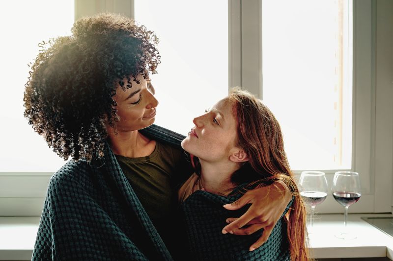 Couple looking at each other in kitchen wrapped in blanket