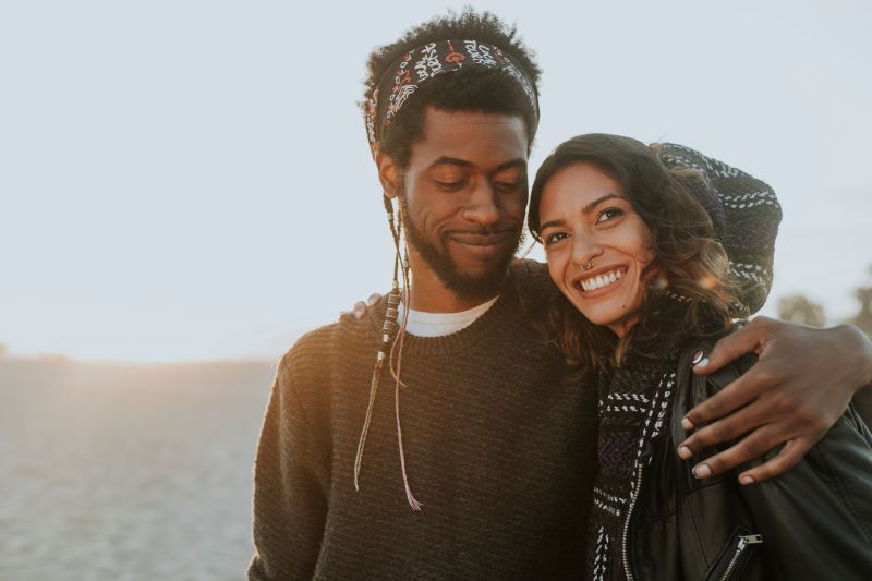 Couple smile and embrace on a beach