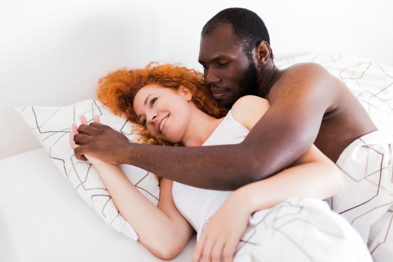 Couple smiling and hugging in bed