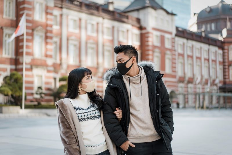 A couple walking outdoors wearing masks