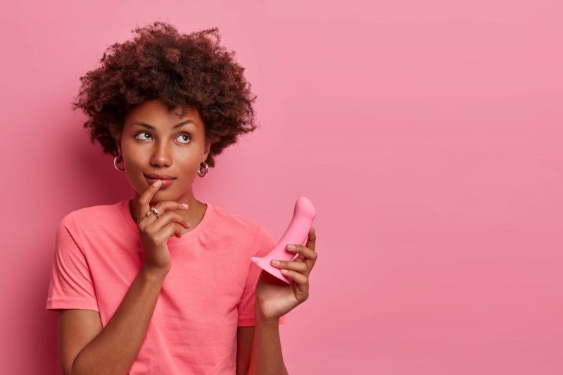 Curious woman holding pink dildo