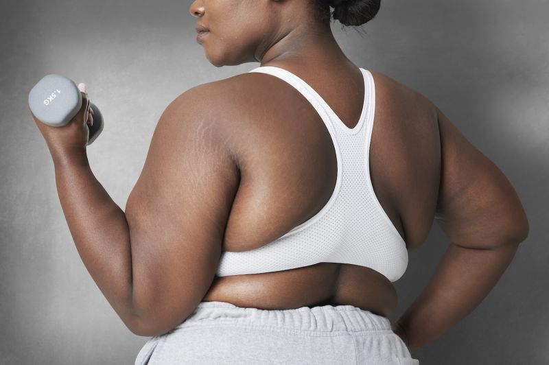 Curvy woman doing dumbbells in sportswear