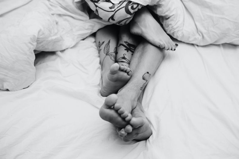 Feet of tattooed couple in bed
