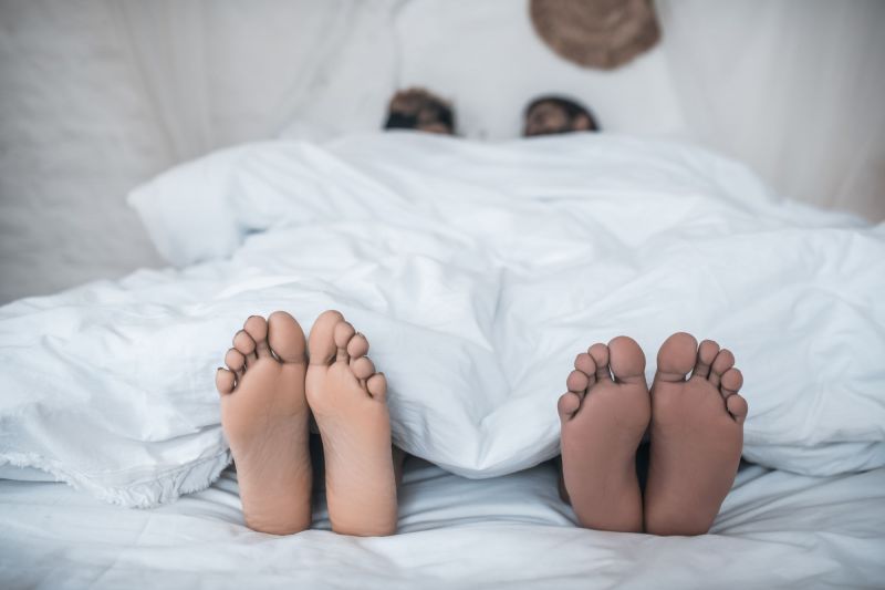 Couple's feet coming out of duvet