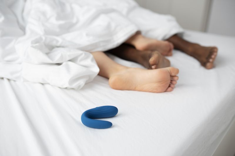 Couple's feet in bed with blue sex toy