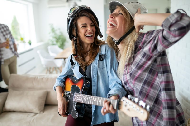 Friends laughing while playing guitar at home