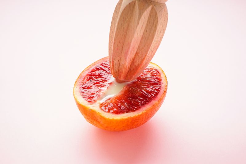 Wooden juicer entering grapefruit sex concept