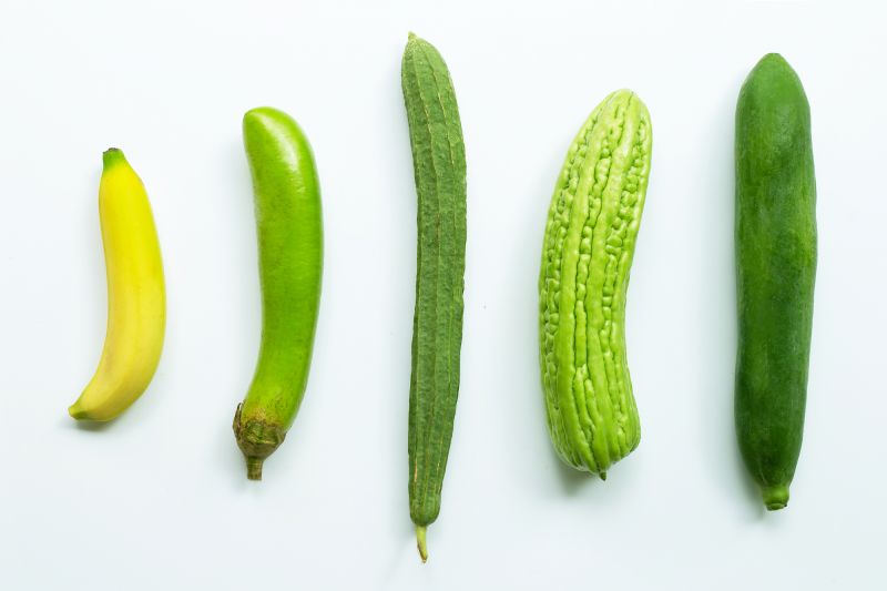 Green phallic fruit and vegetables on white table