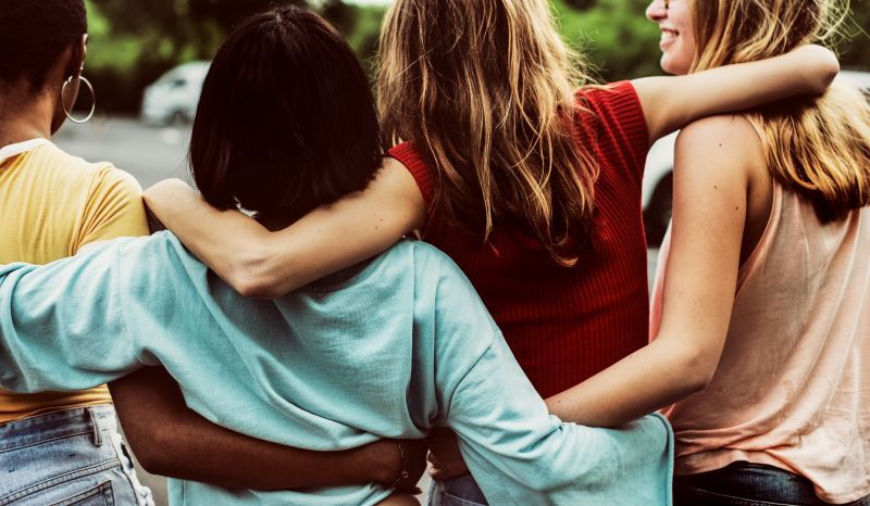 Group of female friends hugging and walking