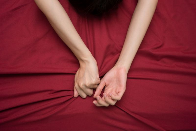 Hand grasping red bed sheet