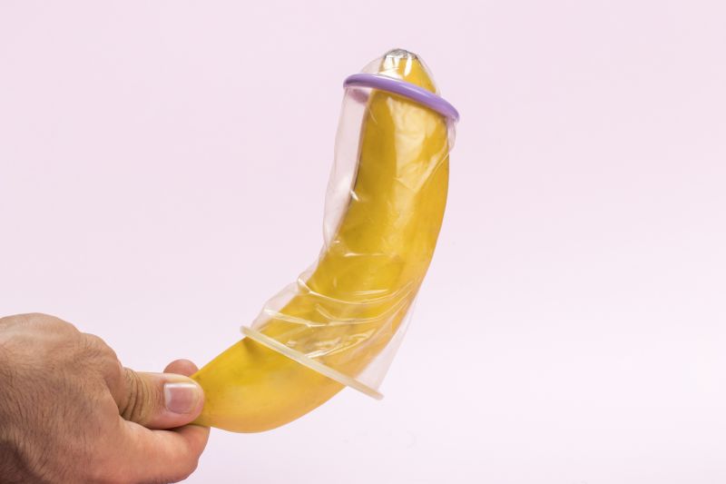 Hand holding banana in condom