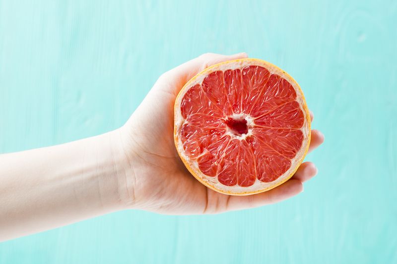 Hand holding half a grapefruit