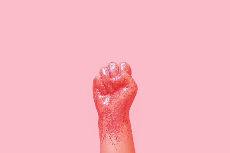 Hand making fist covered in pink glitter