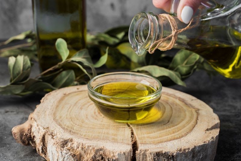 Hand pouring olive oil into jar