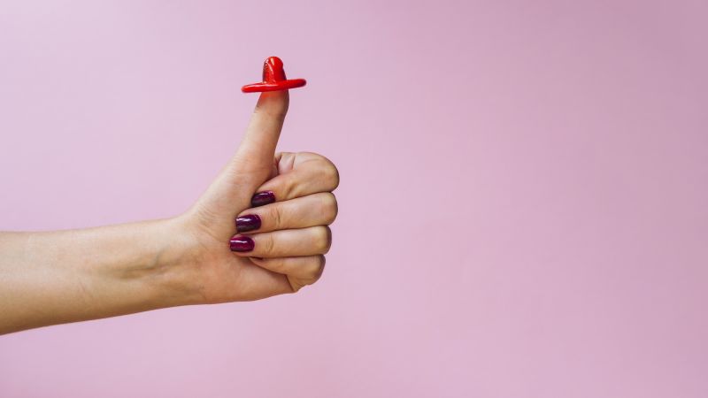 Hand with condom doing thumbs up