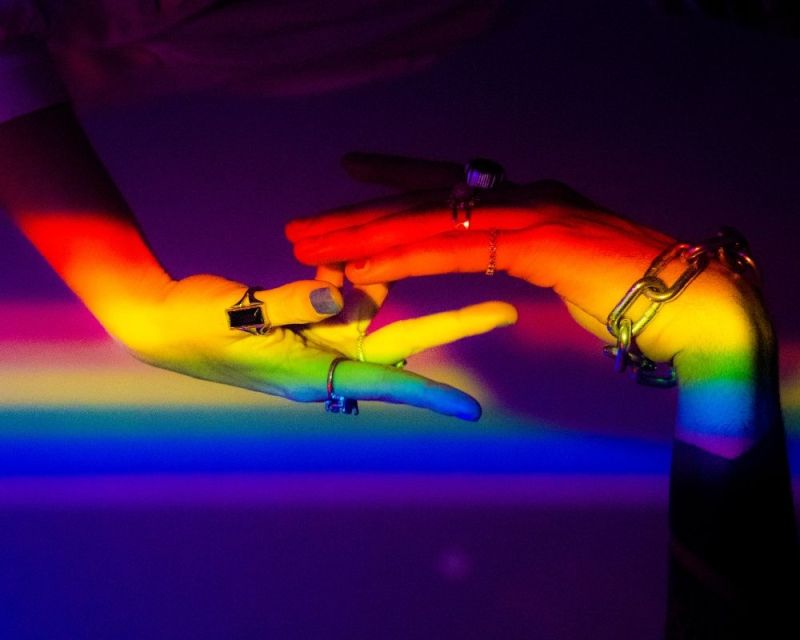 hands touching in rainbow light