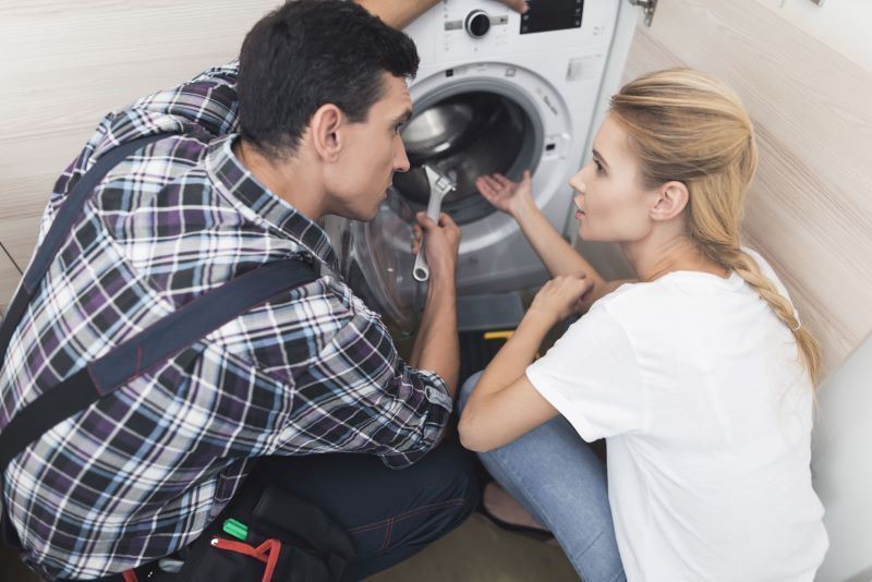 Handyman helps woman with washing machine