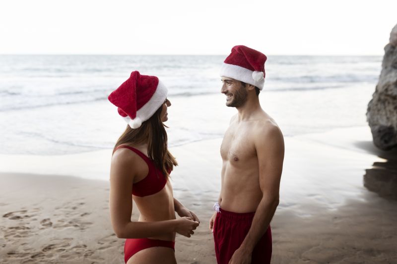 happy couple in santa hats by the sea